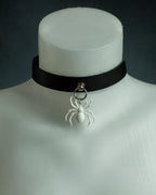 Close-up of the Arachne black leather choker with a white spider pendant on silver hardware