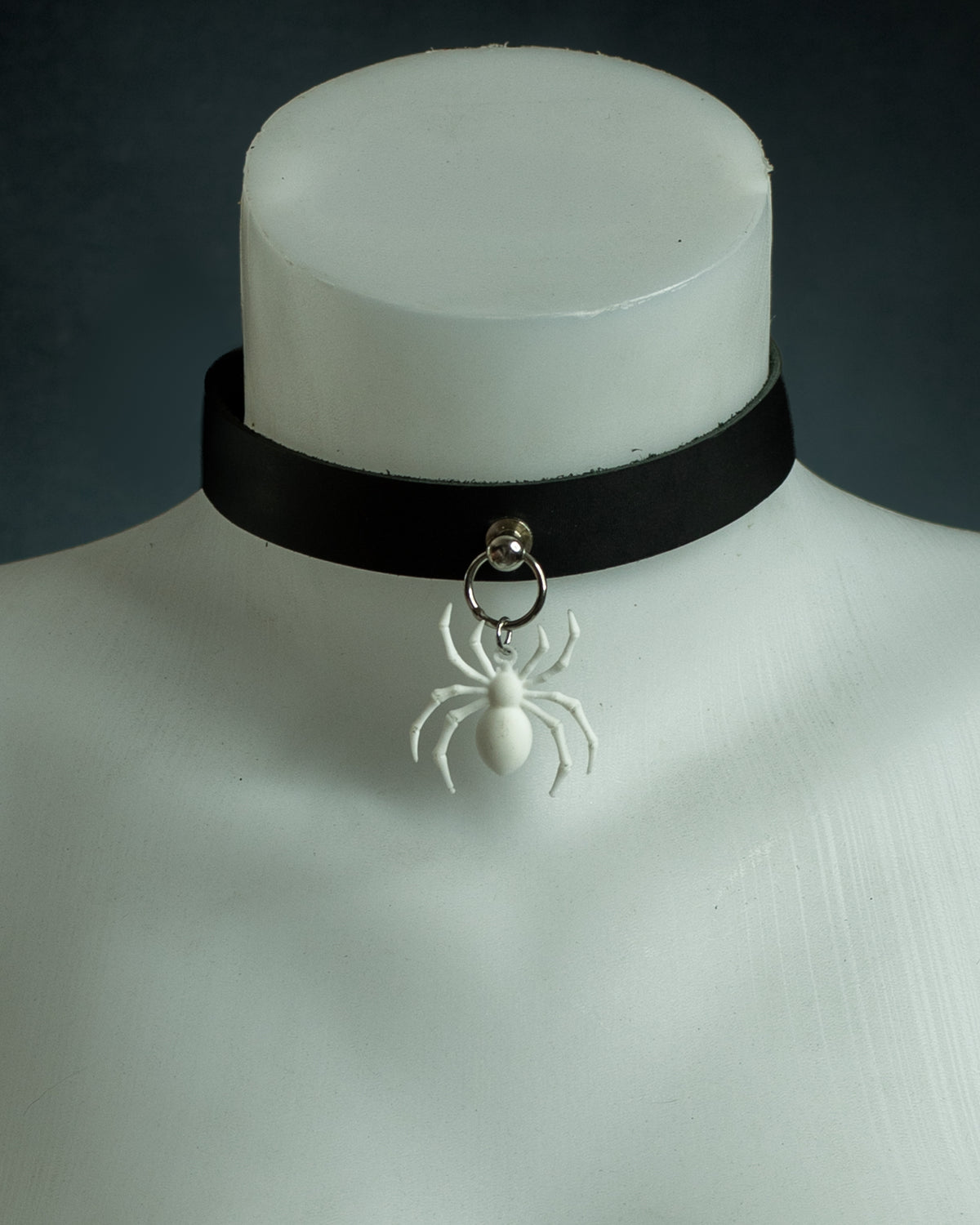 Close-up of the Arachne black leather choker with a white spider pendant on silver hardware
