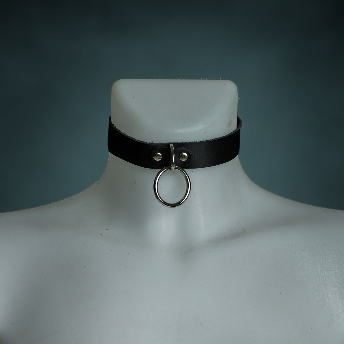 Black leather O-ring choker with silver hardware on a white mannequin, front view, by Wandering Chaos