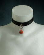 Close-up of the Samhain black leather choker with an orange jack-o'-lantern bell on silver hardware
