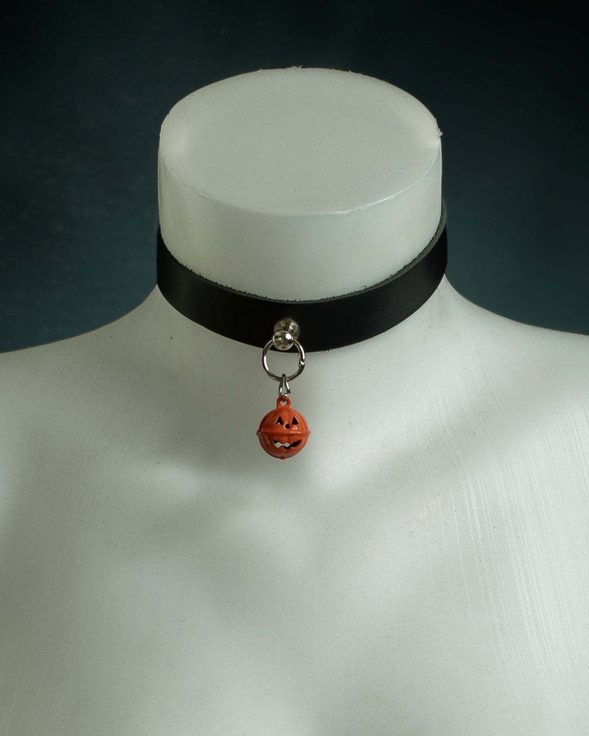 Close-up of the Samhain black leather choker with an orange jack-o'-lantern bell on silver hardware