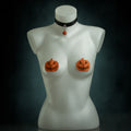 Samhain pumpkin set: black leather choker with an orange jack-o'-lantern bell and orange leather pumpkin pasties by Wandering Chaos