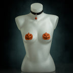 Samhain pumpkin set: black leather choker with an orange jack-o'-lantern bell and orange leather pumpkin pasties by Wandering Chaos