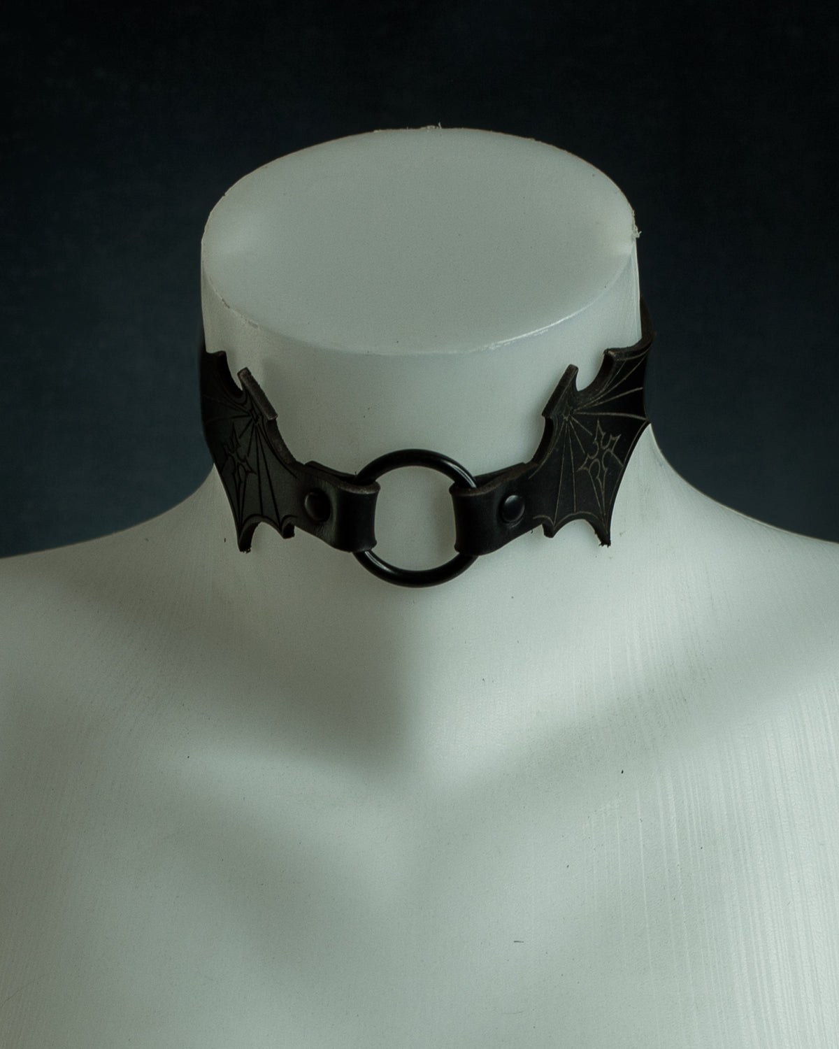 Close-up of the Vesper black leather bat wing choker with etched gothic pattern and black O-ring